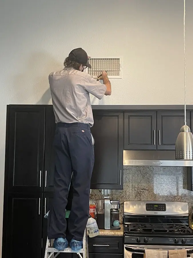 Technician inspecting an air vent during HVAC service in Newtown